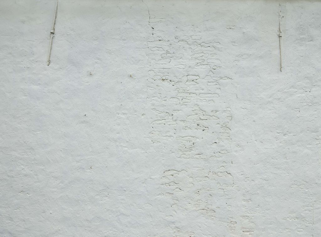 Ściana z białym stiukiem i kotwami ściennymi