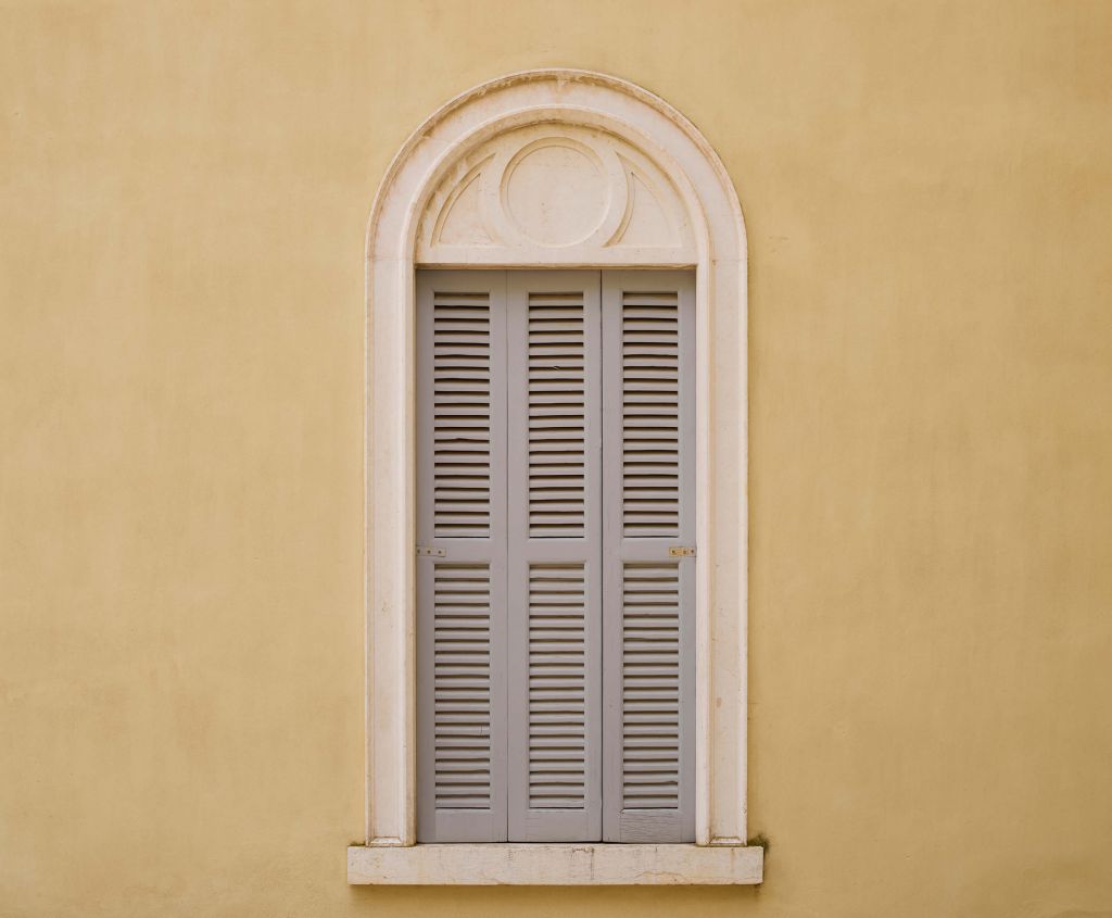 Okno z drewnianymi okiennicami na żółtej ścianie