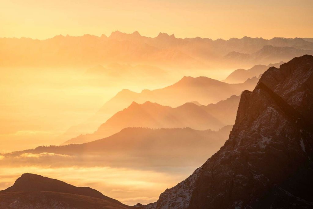 Złocisty blask nad warstwami gór.