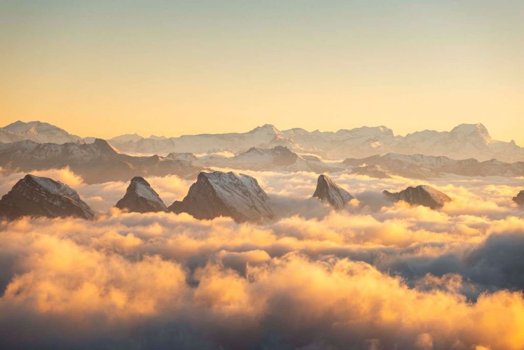 Szczyty gór nad złotym morzem chmur.