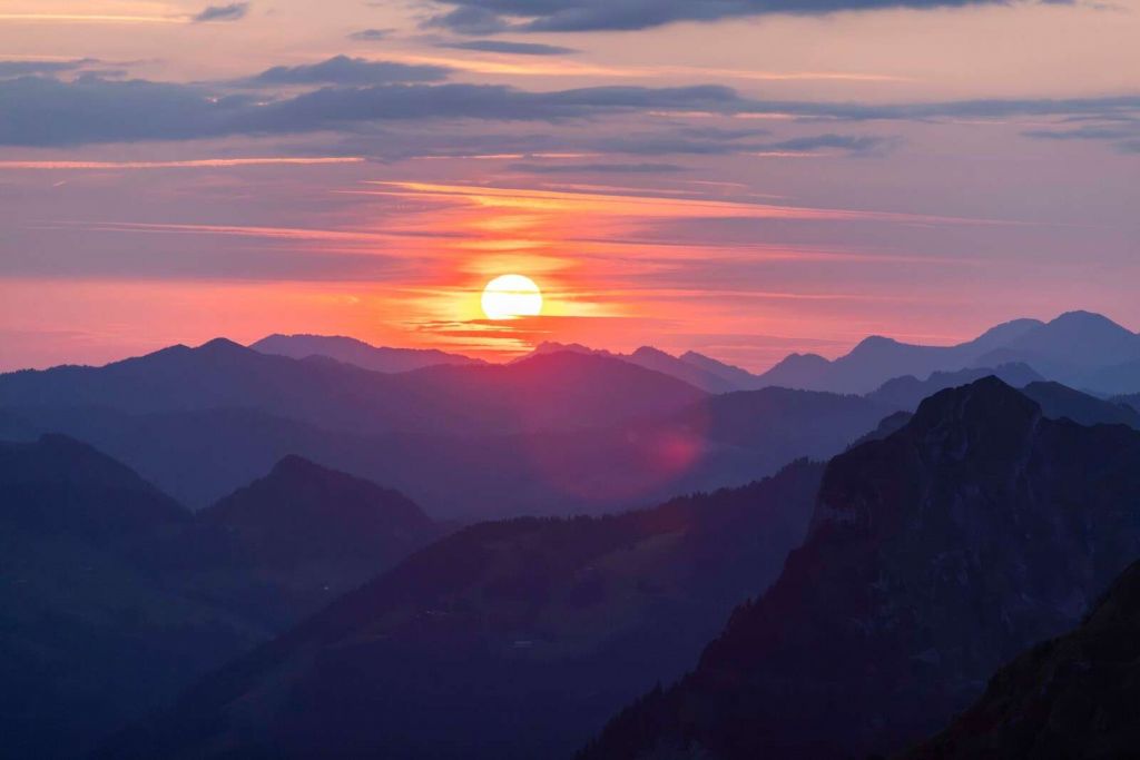 Zachód słońca nad fioletowymi warstwami gór.