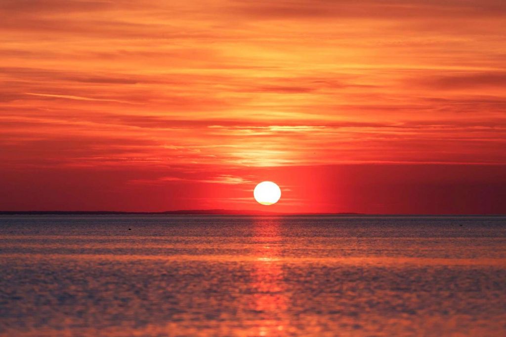 Czerwony zachód słońca nad spokojnym morzem.