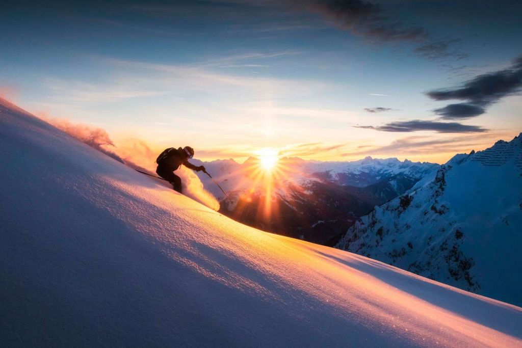 Narciarz w ognistym słońcu gór.