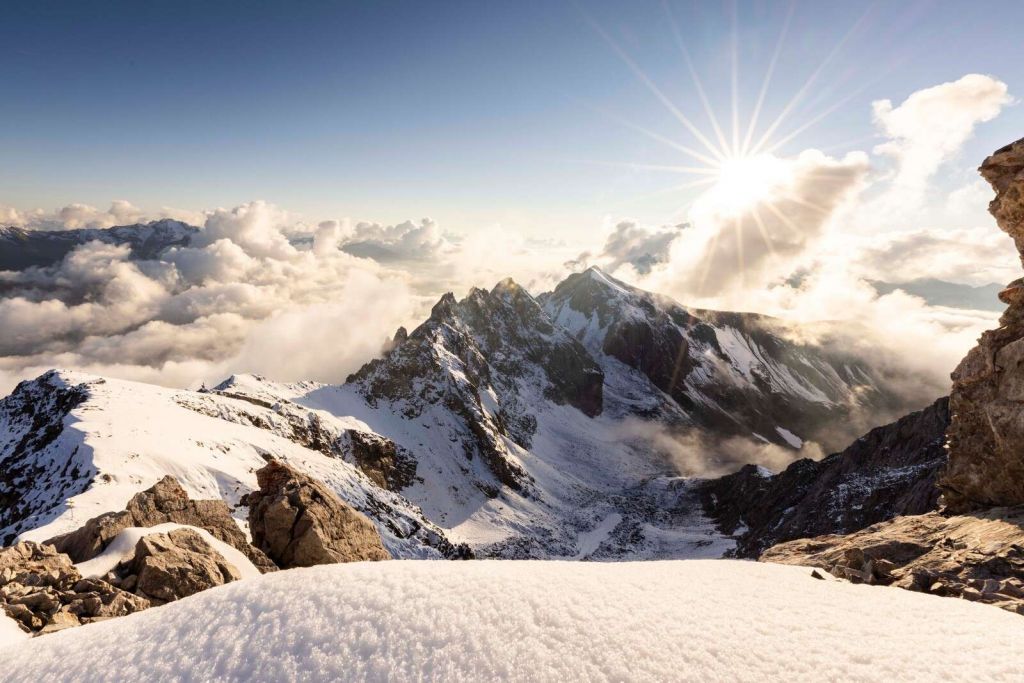 Światło słoneczne nad zaśnieżonym grzbietem gór.