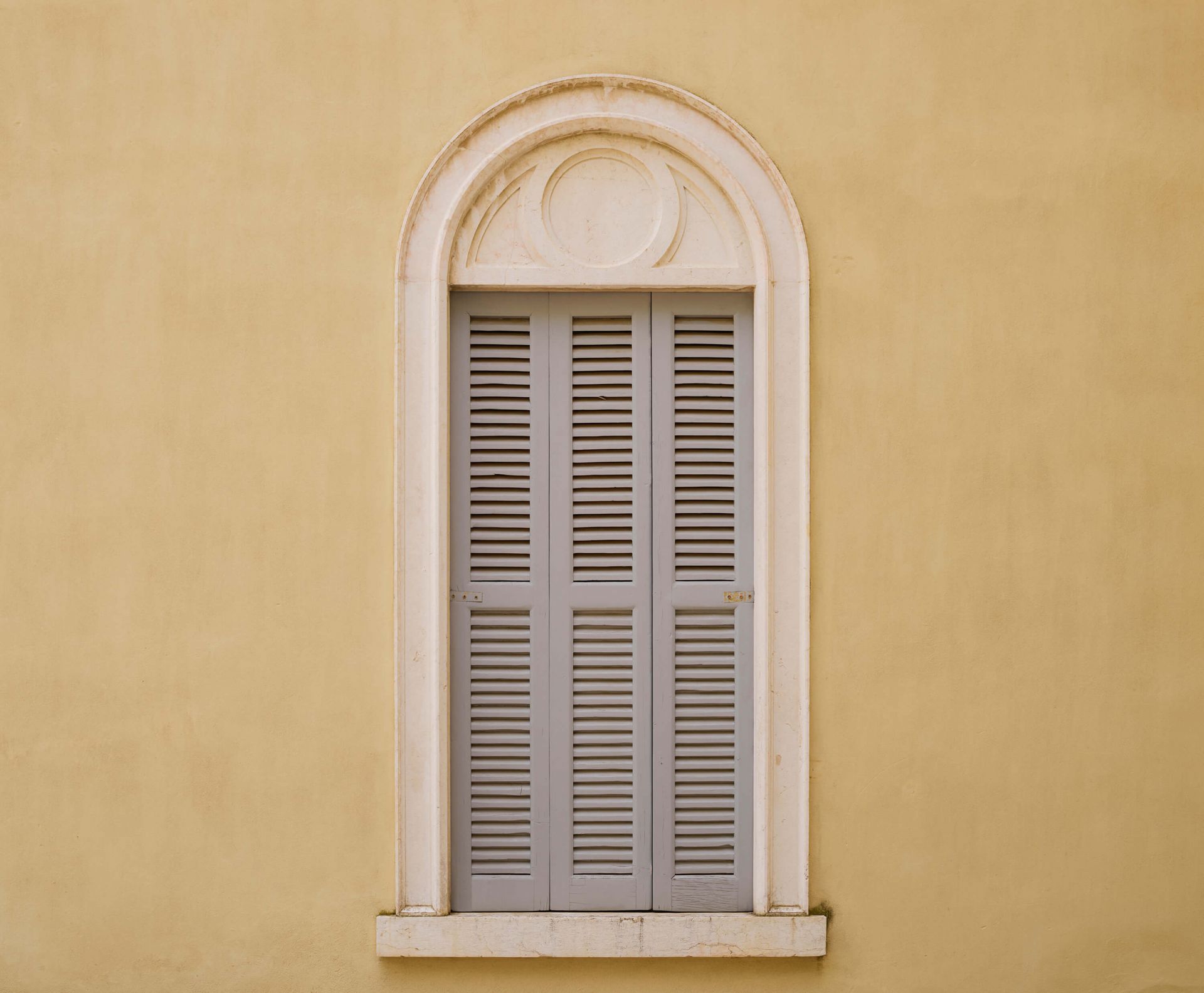 Okno z drewnianymi okiennicami na żółtej ścianie