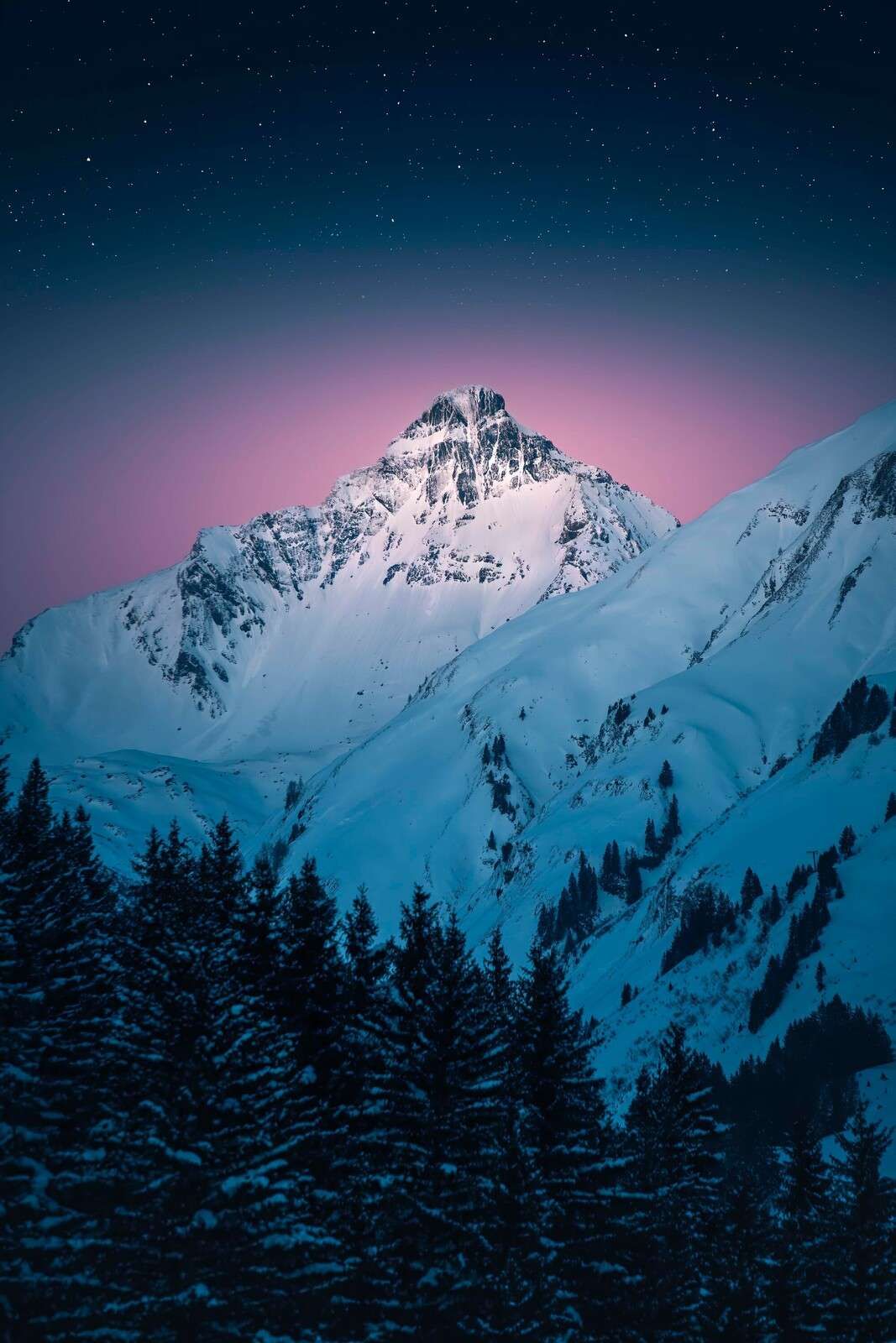 Zasnieżony szczyt góry pod gwiaździstym niebem.